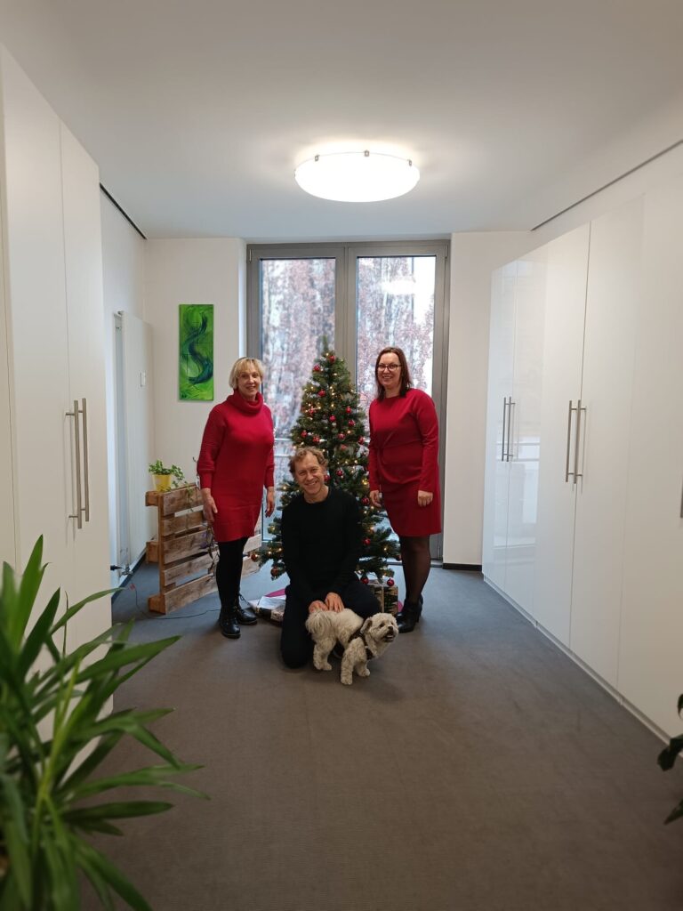 Anja Fischer, Günther holzapfel, Daniela Ettl und Bürohund Korbi vorm Weihnachtsbaum